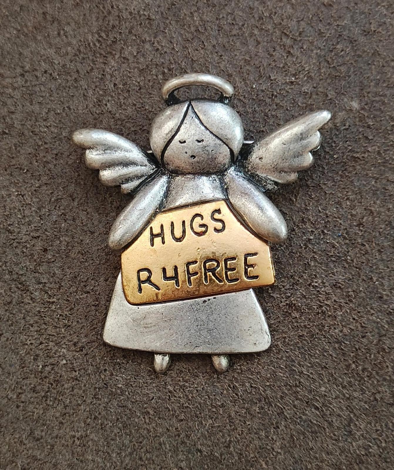Silver angel brooch with wings and tan front panel stamped HUGS R4FREE