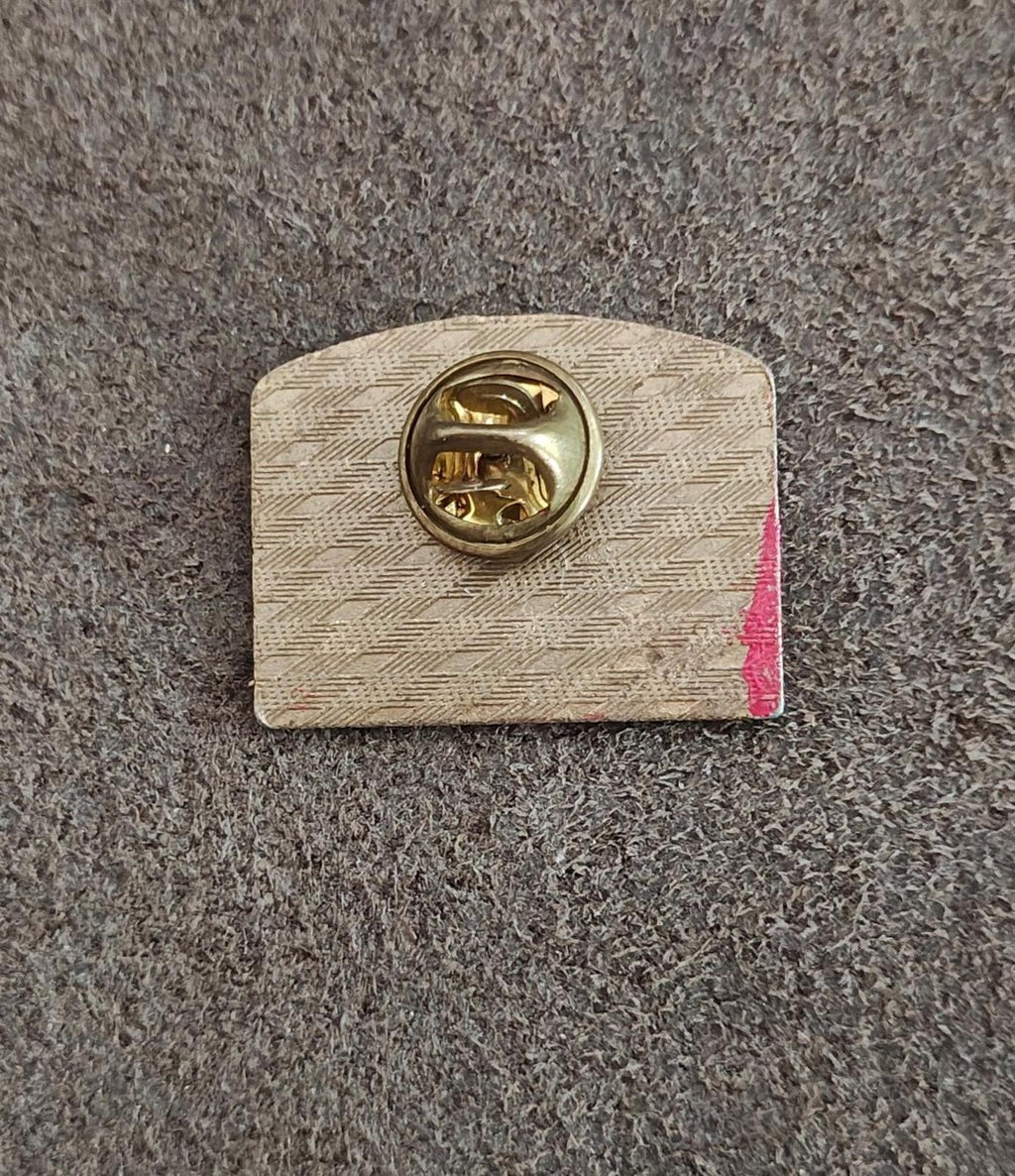 Gold-tone pin backing with round clasp on textured silver backing