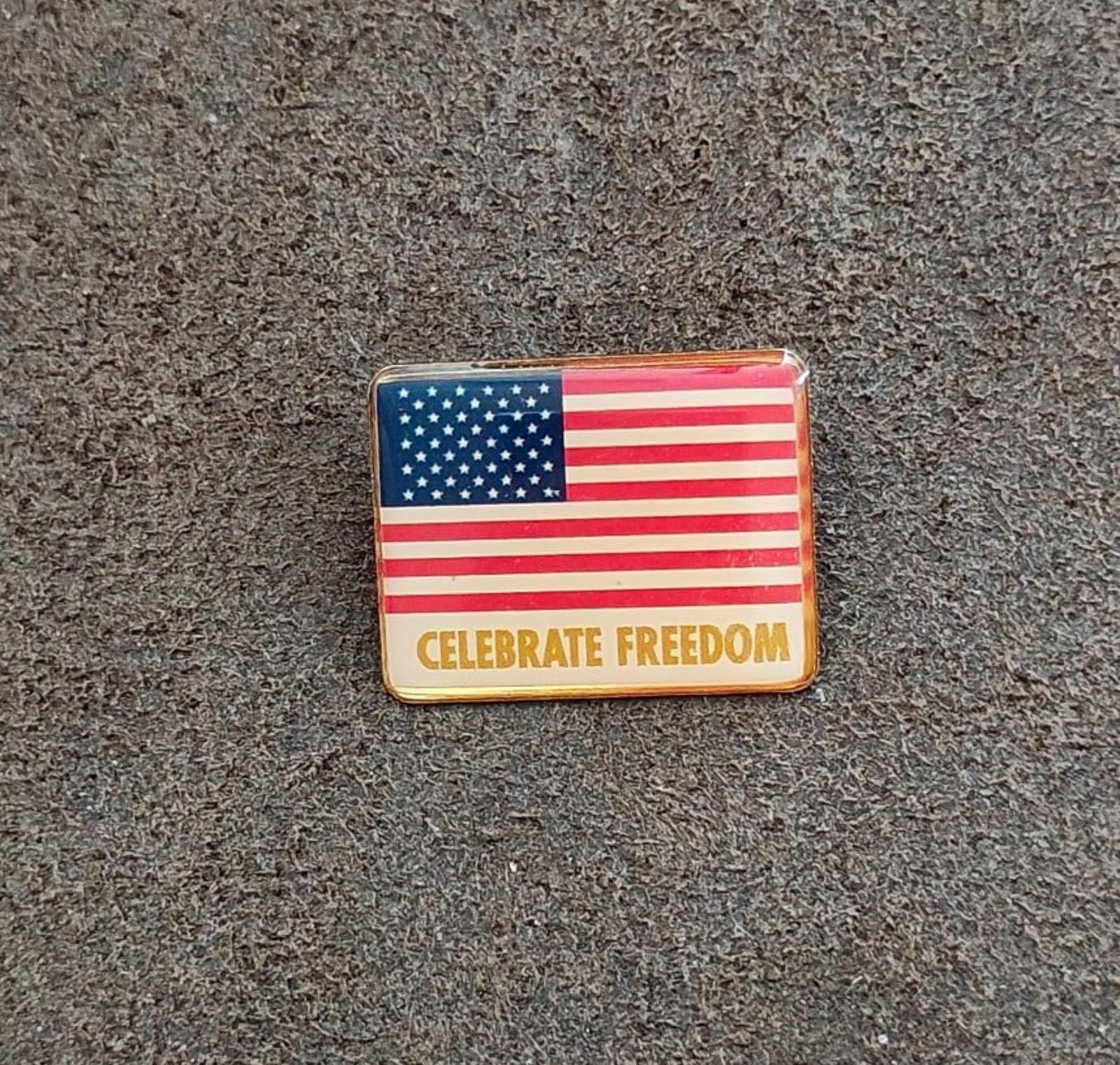 Rectangular gold-tone American flag pin with “CELEBRATE FREEDOM” front text