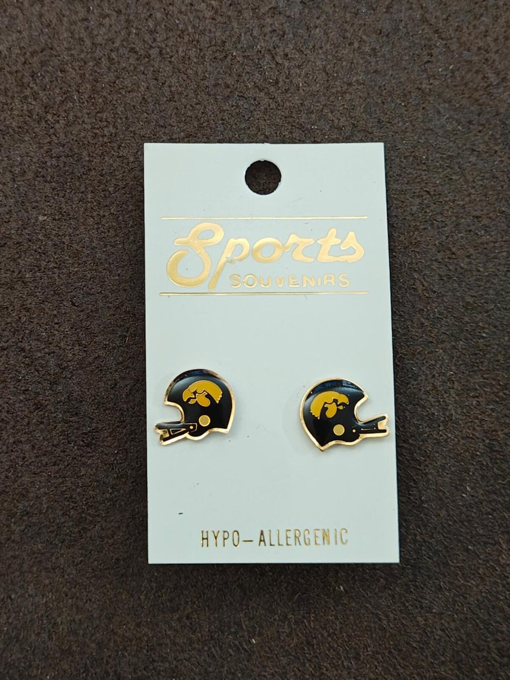 Helmet-shaped gold-tone enamel stud earrings on a hanging backing card