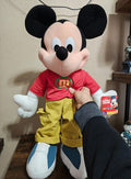 Mickey Mouse plush in red T-shirt, yellow shorts, and blue-and-white shoes with tag