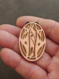 Apricot oval pin with intricate leaf-and-vine cutout and gold-tone border