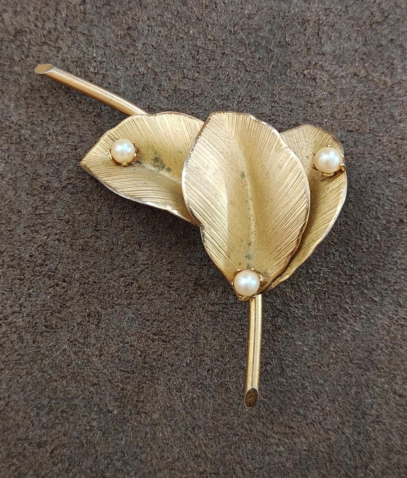 Gold leaf brooch with textured petals, three faux pearls, and a vertical stick pin