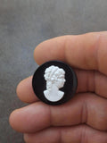 Black round cameo brooch with white profile of a woman head relief