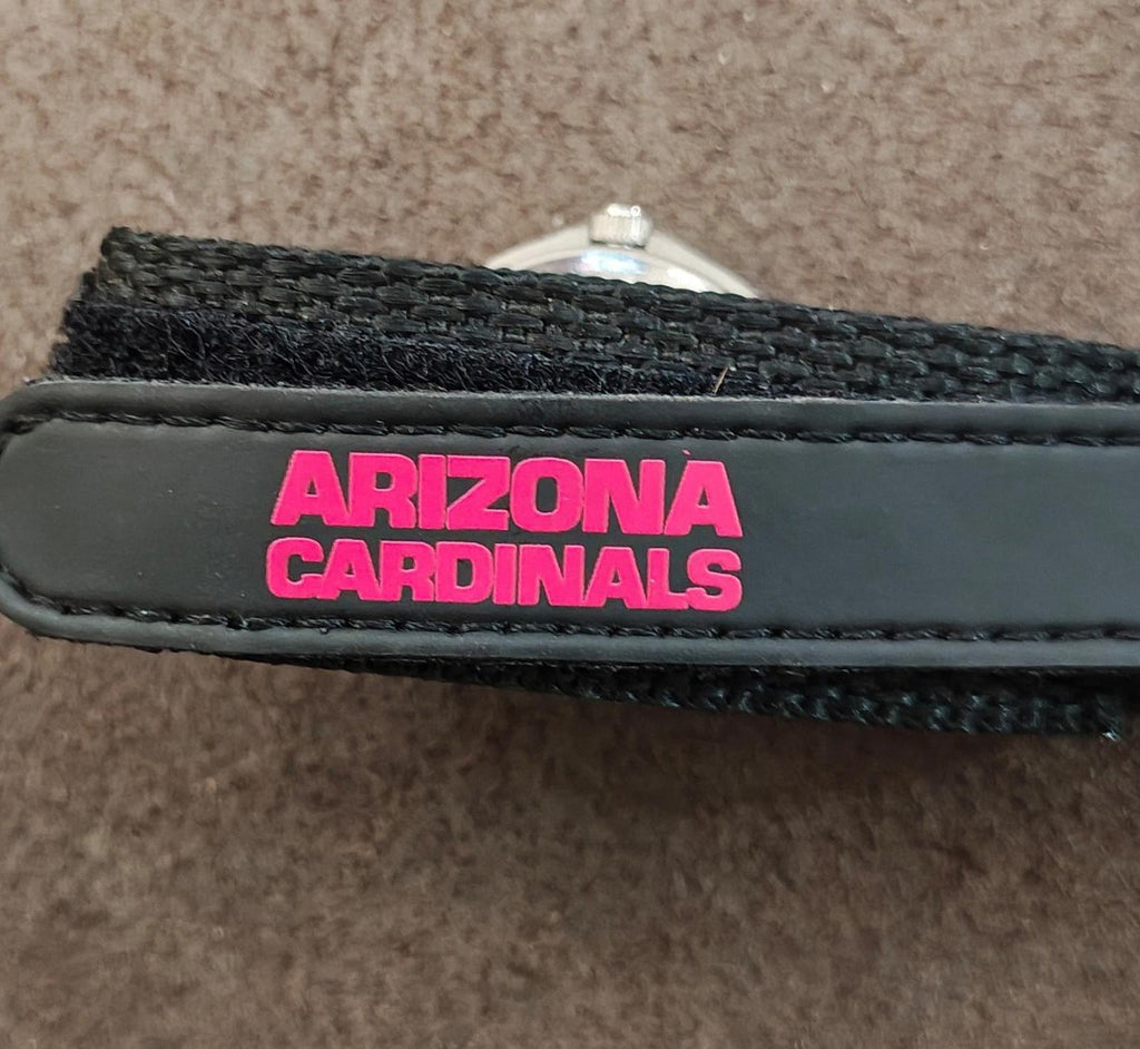 Black watch strap with pink “ARIZONA CARDINALS” text label near metal buckle