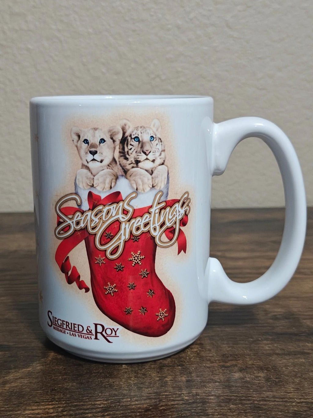 White porcelain mug on tabletop with two big cats and red “Seasons Greetings” stocking graphic