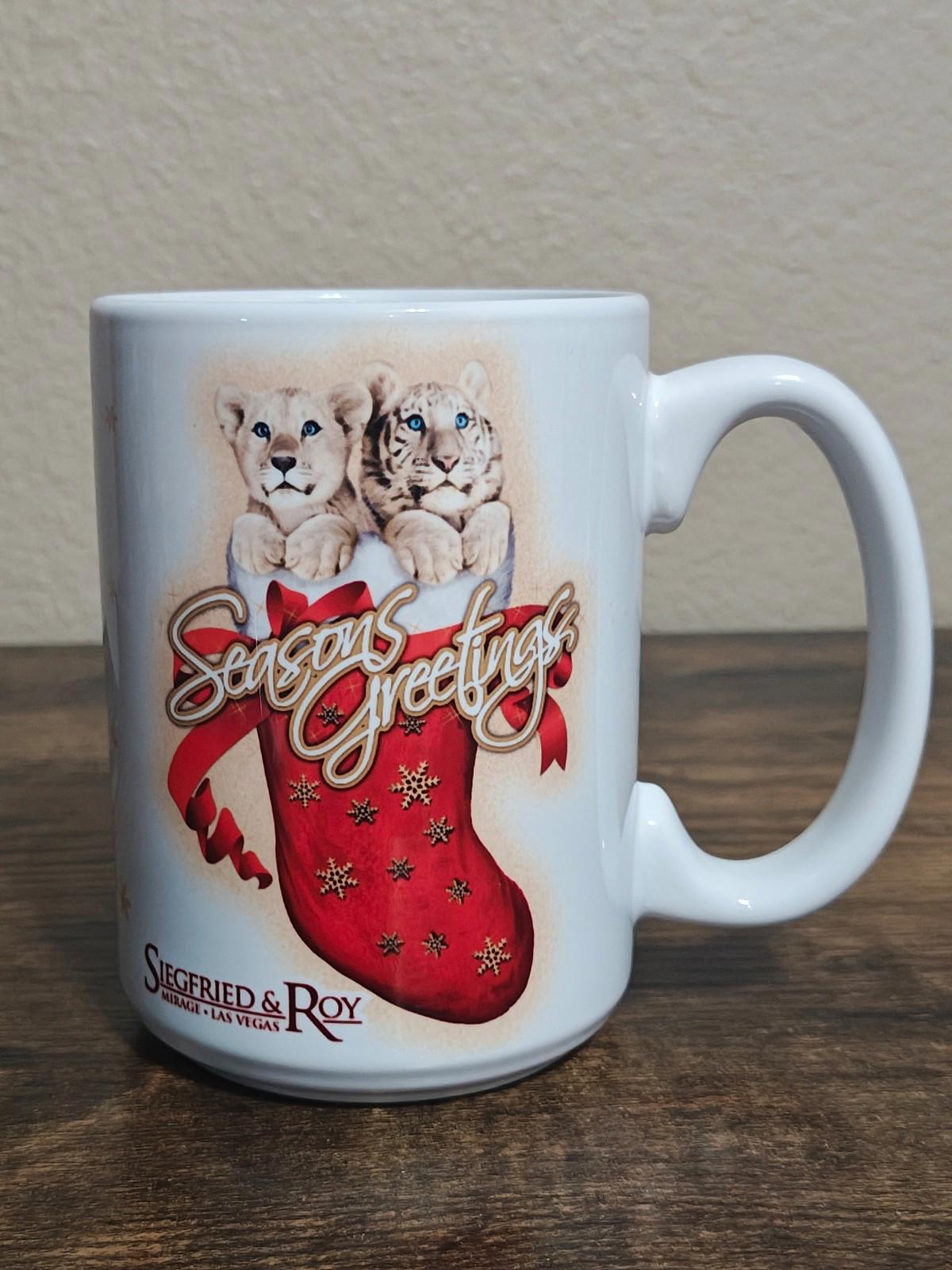 White porcelain mug on tabletop with two big cats and red “Seasons Greetings” stocking graphic