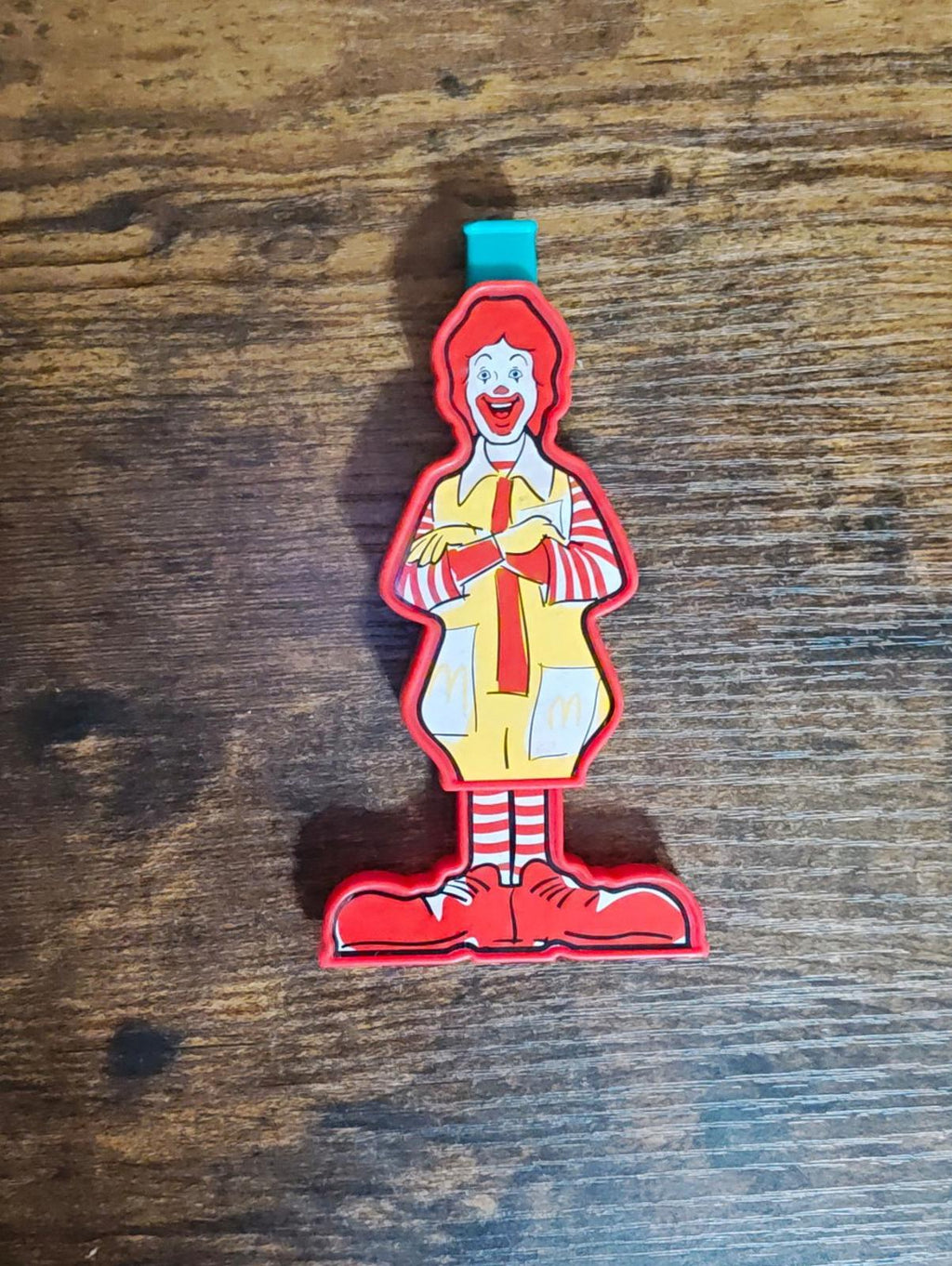 Full front view of Ronald McDonald slide whistle on red base with teal mouthpiece.