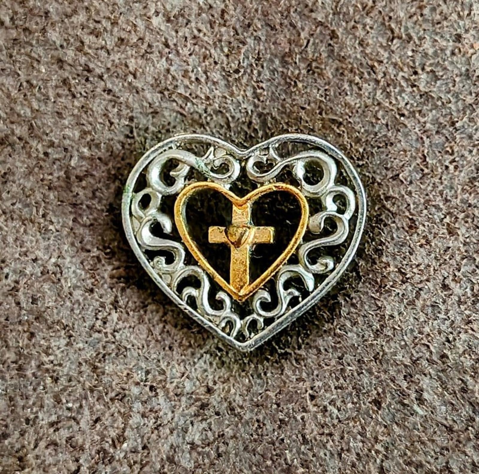 Heart cross pin on textured surface; silver filigree with gold-toned heart and cross
