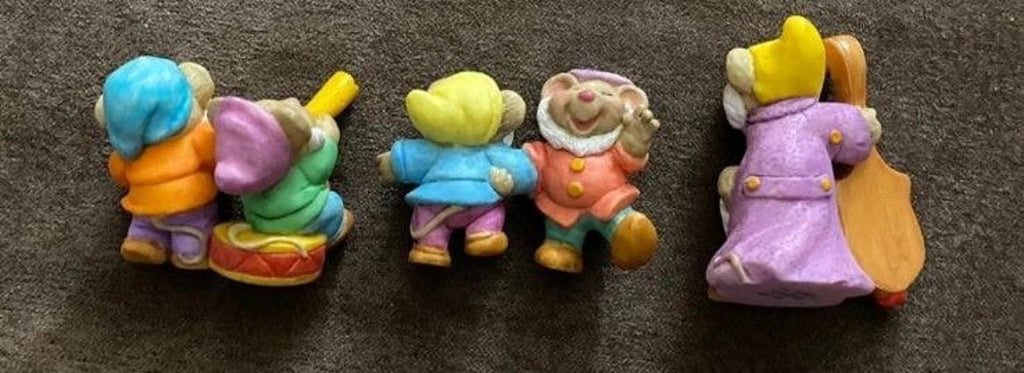 Three dwarf figurines in blue, green, and purple outfits with a harp figure on the right.