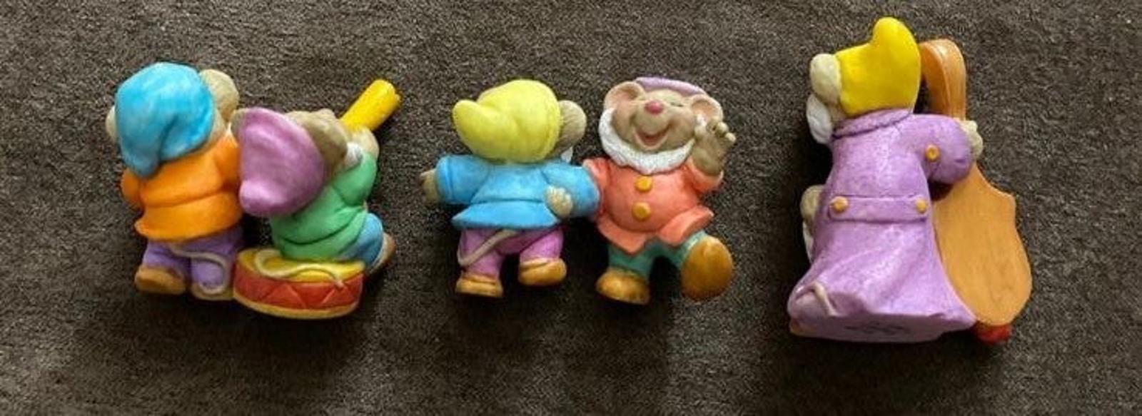 Three dwarf figurines in blue, green, and purple outfits with a harp figure on the right.