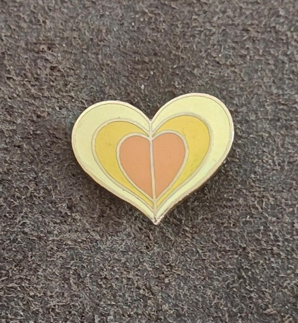 Gold tone enamel heart pin with yellow detailing and orange inner heart.