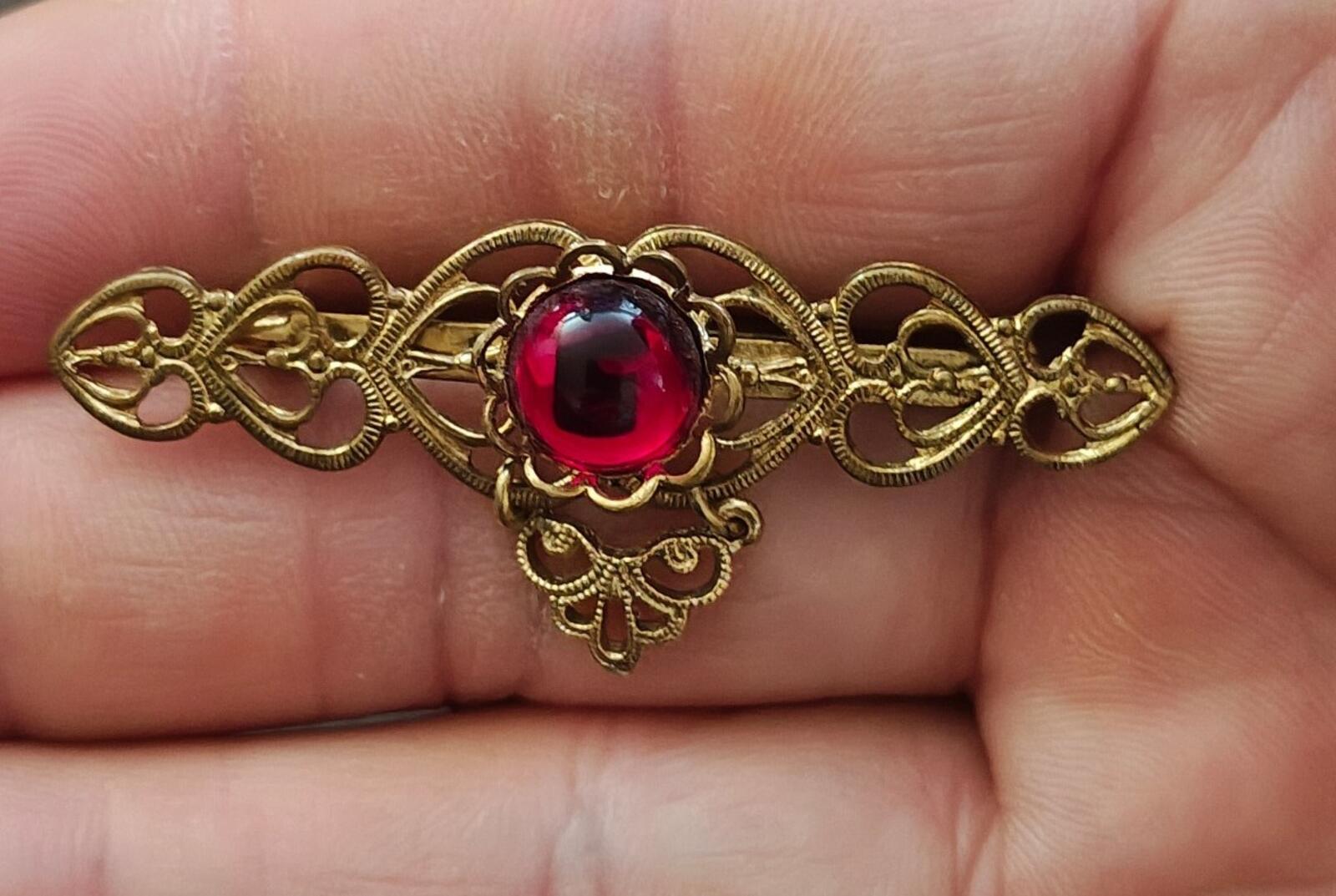 Gold-tone filigree heart brooch with open hearts and round red jelly cabochon