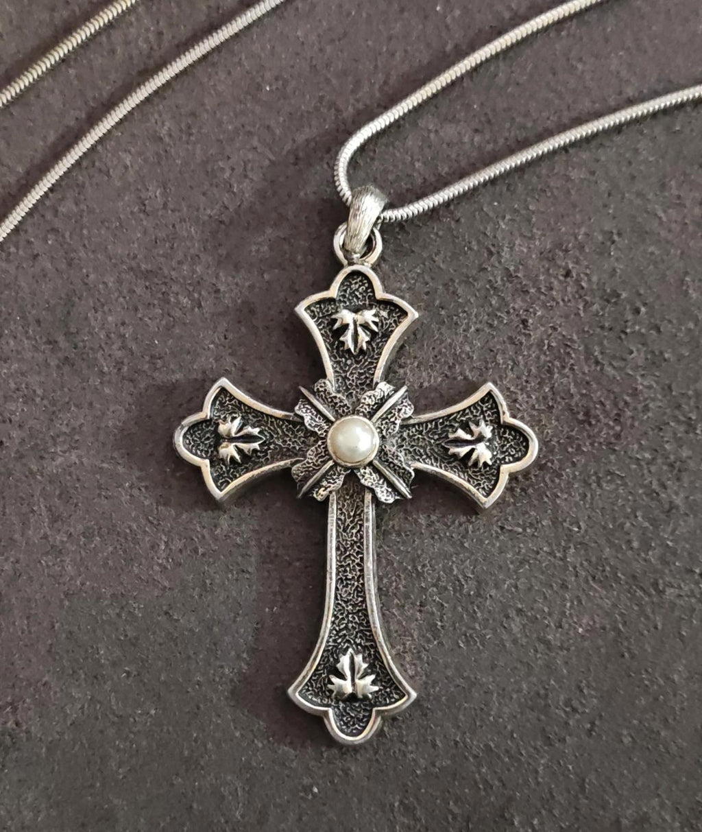 Silver tone cross pendant necklace with faux pearl and decorative star accents on bail