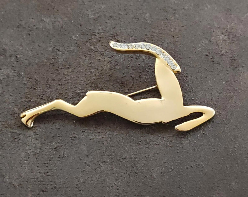 Gold-tone leaping gazelle/impala brooch with sparkling rhinestone accents, angled view