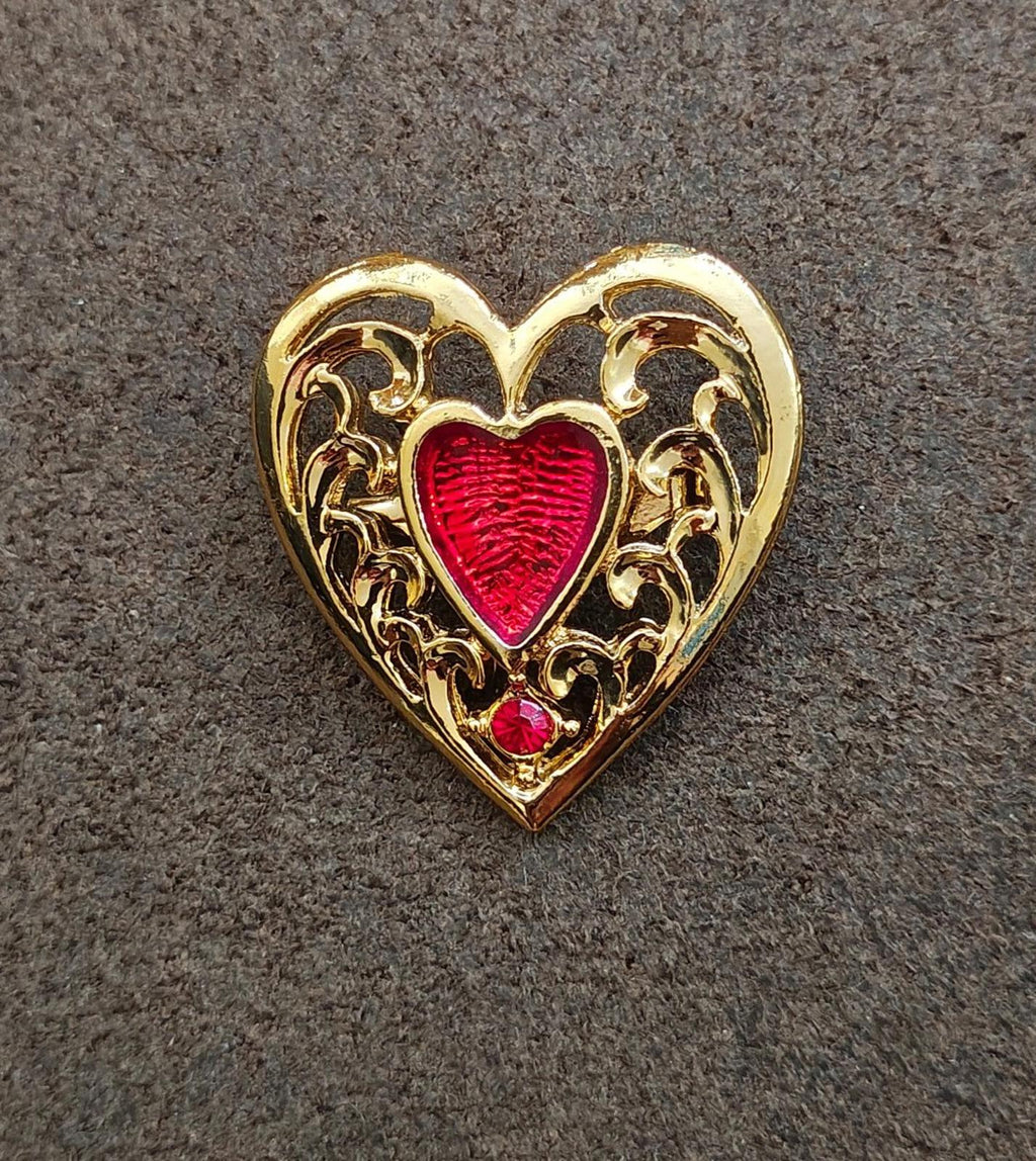 Heart-shaped gold-tone brooch with red enamel heart center and intricate cutout scrolls