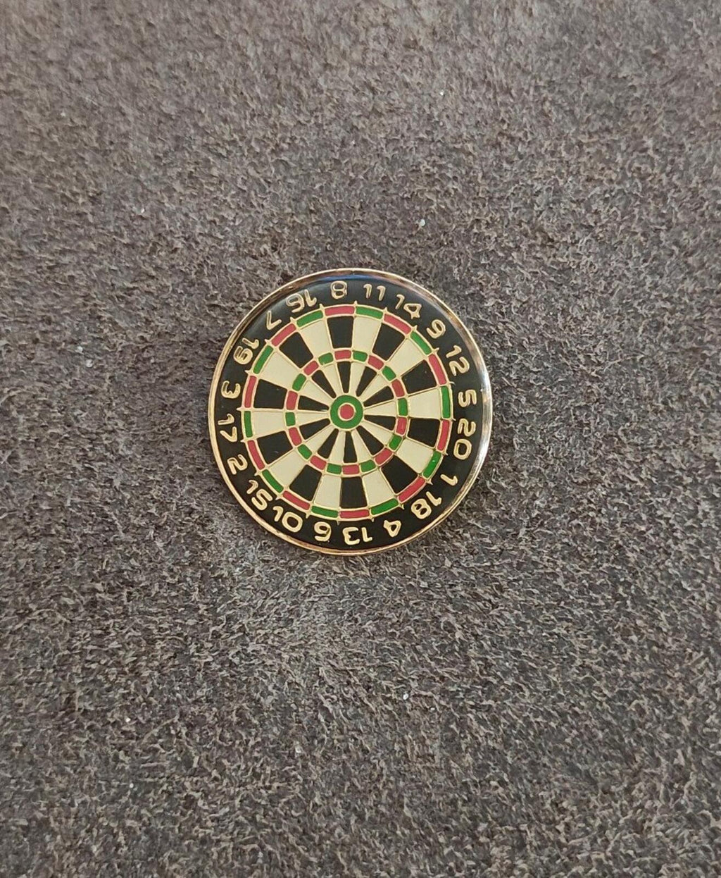 Small gold-tone dartboard enamel pin, visible multicolor grid spokes and outer number band.