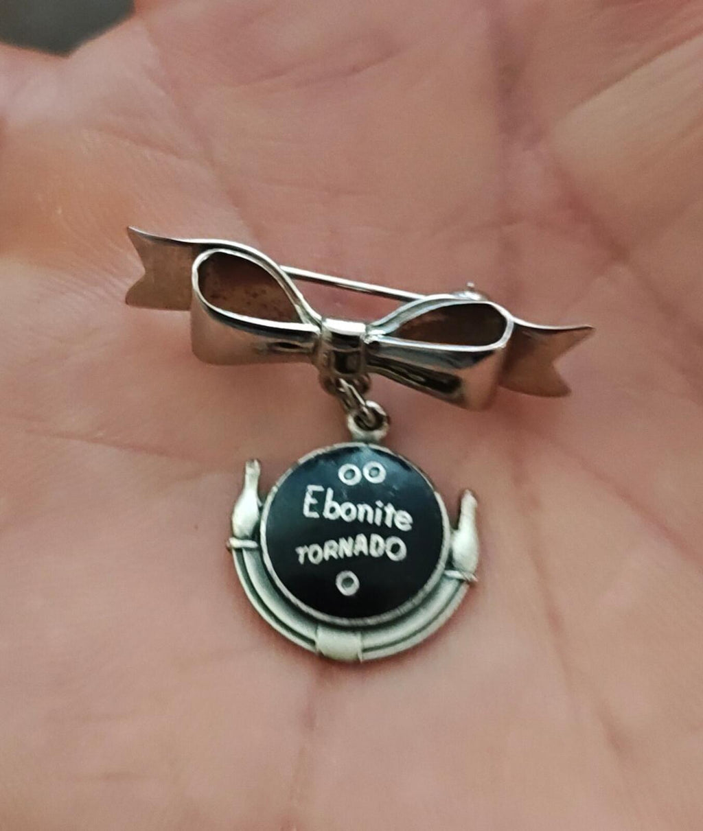 Silver tone bow bar pin with Ebonite Tornado round dangle charm