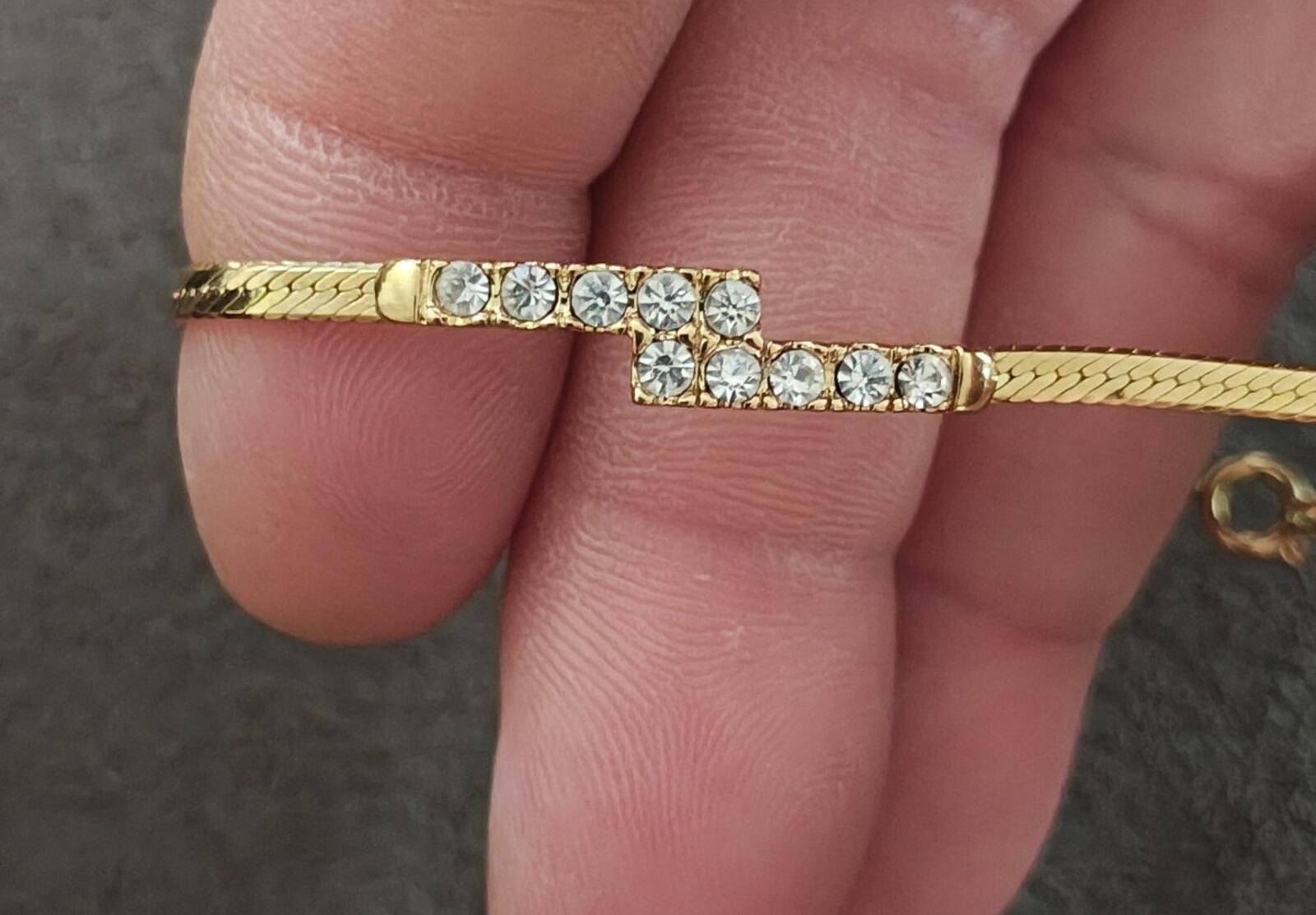Gold tone crossover bracelet with crystal rhinestone row on bar, close-up