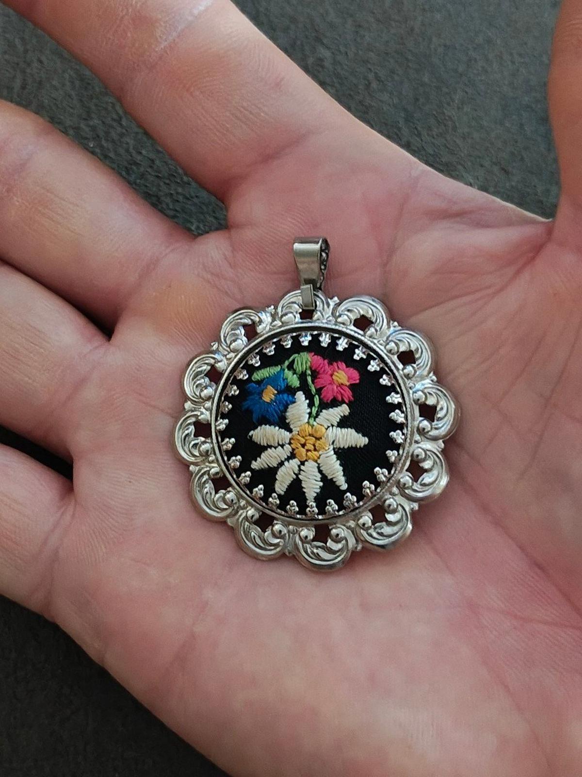 Silver filigree pendant, round black embroidered flower with colorful blossoms and bail.