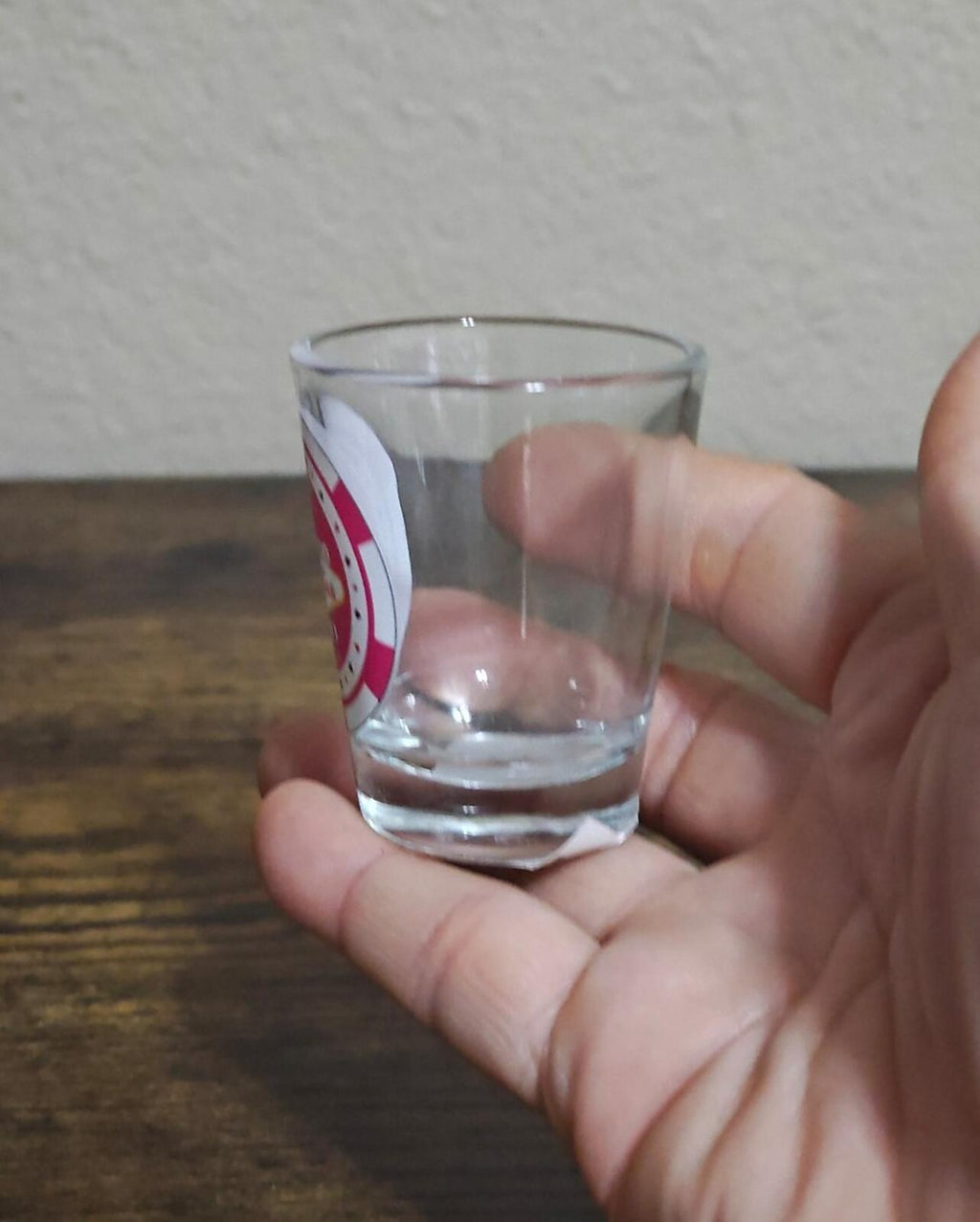 Clear shot glass in hand, front design not visible