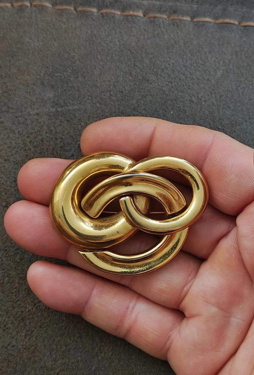 Gold-tone intertwined circle pin brooch with glossy textured finish