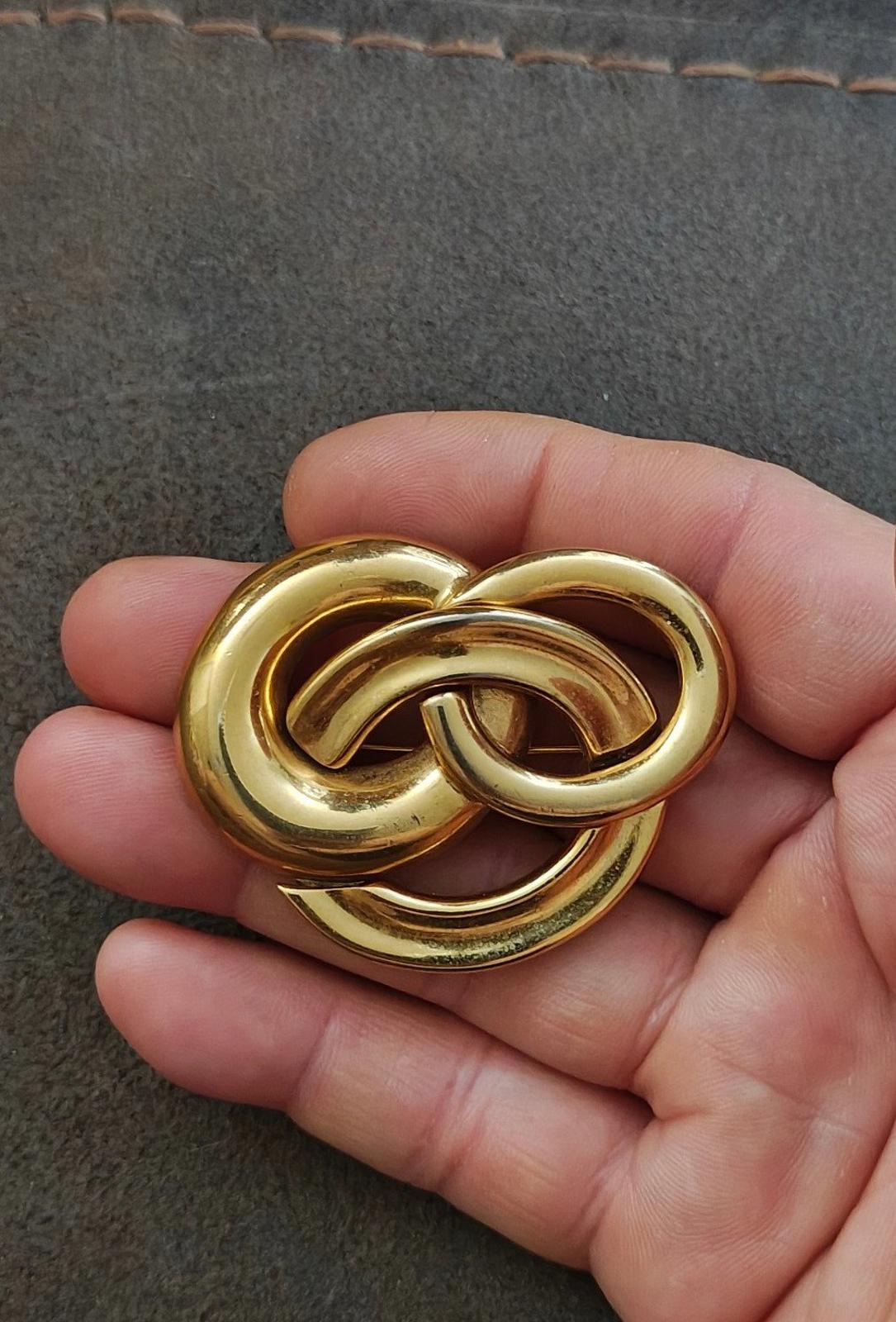 Gold-tone intertwined circle pin brooch with glossy textured finish