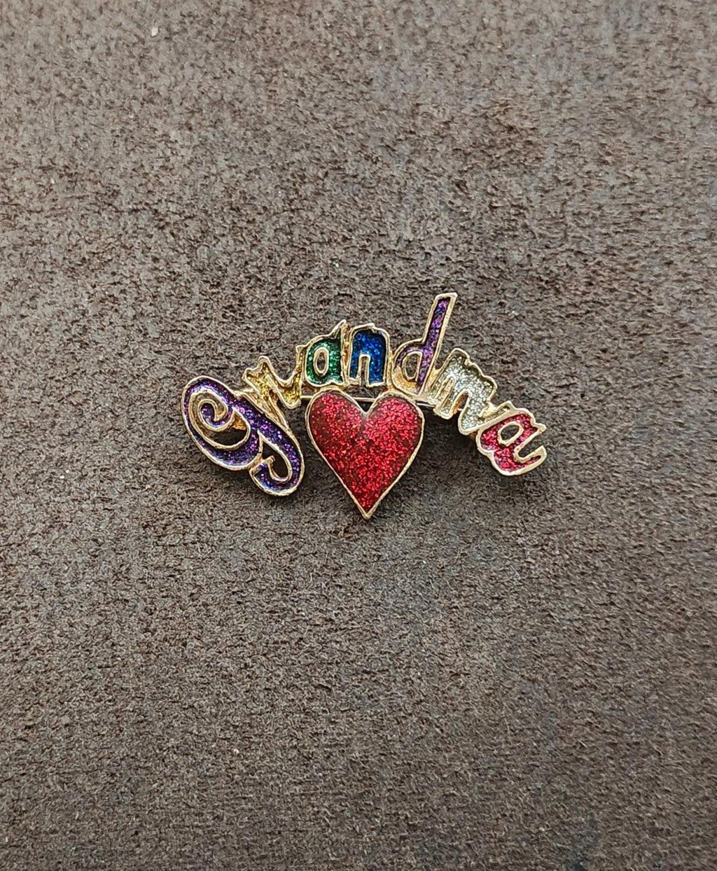 Gold tone grandma brooch featuring a red glitter heart and rainbow enamel lettering