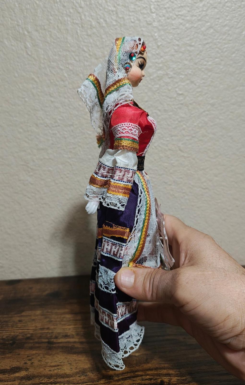 Female folk doll in red bodice with multicolor striped sleeves, side profile