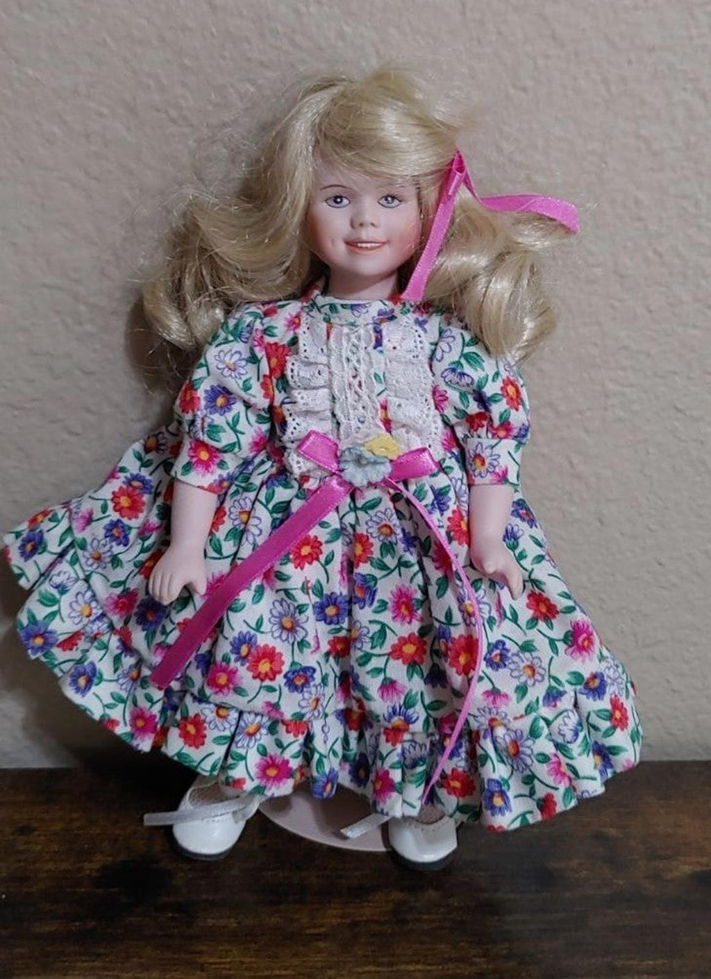 Porcelain doll 3/4 view with long blonde hair curls and pink ribbon dress details