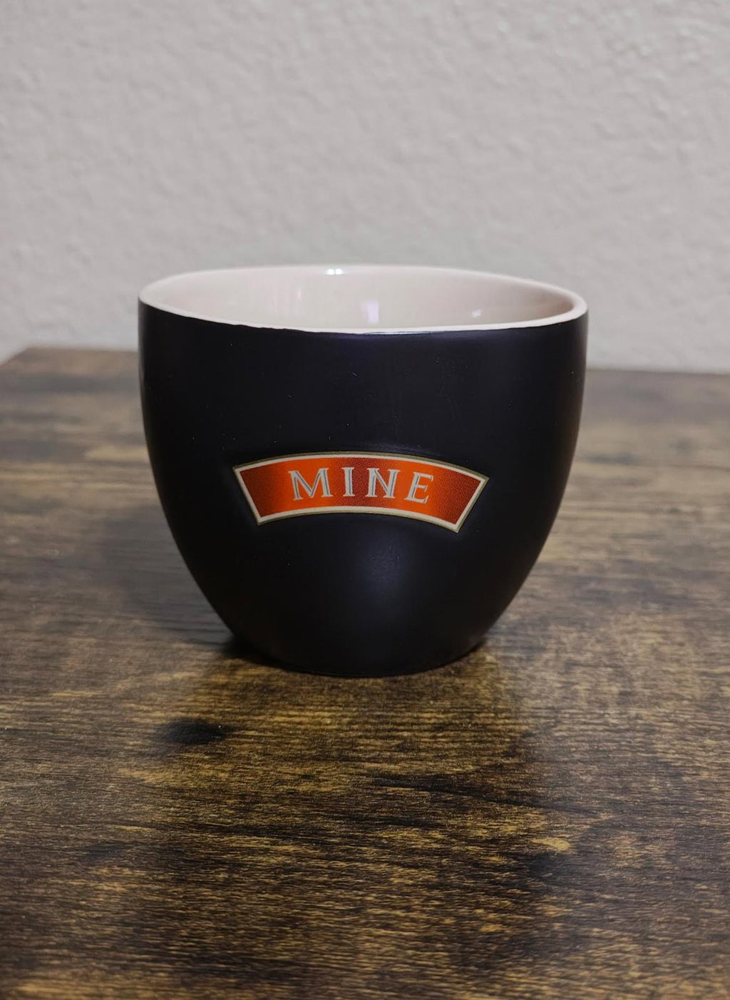 Black stoneware cup with 'Mine' orange badge on front
