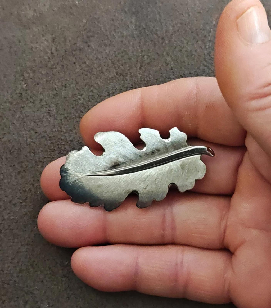 Silver tone leaf brooch on fingers, textured leaf shape with metal pin bar