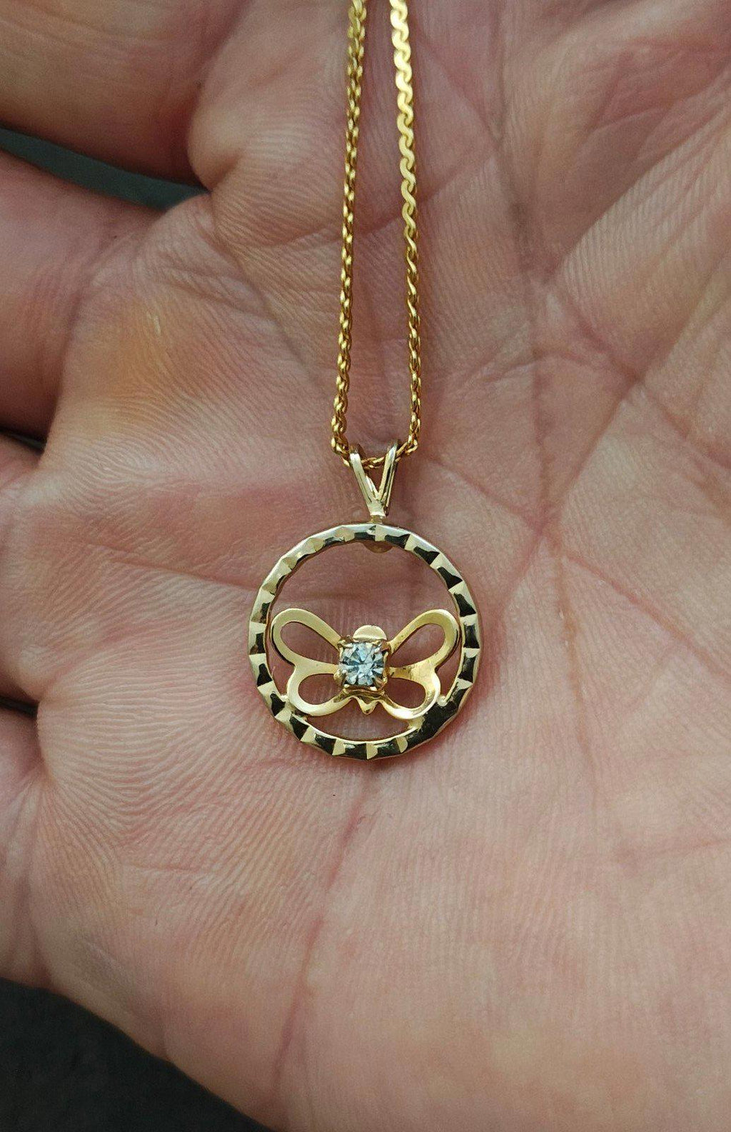 Gold-tone round pendant necklace on chain, open circle design with clear rhinestone butterfly
