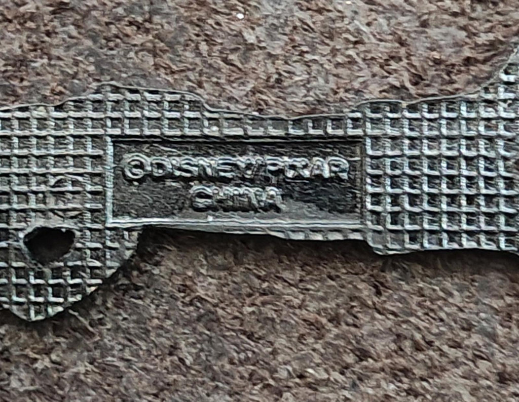 Metal pin backing with engraved markings and two long notches