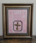 Pink framed cross wall art with gold-tone cross and “LOVE” text in vintage frame