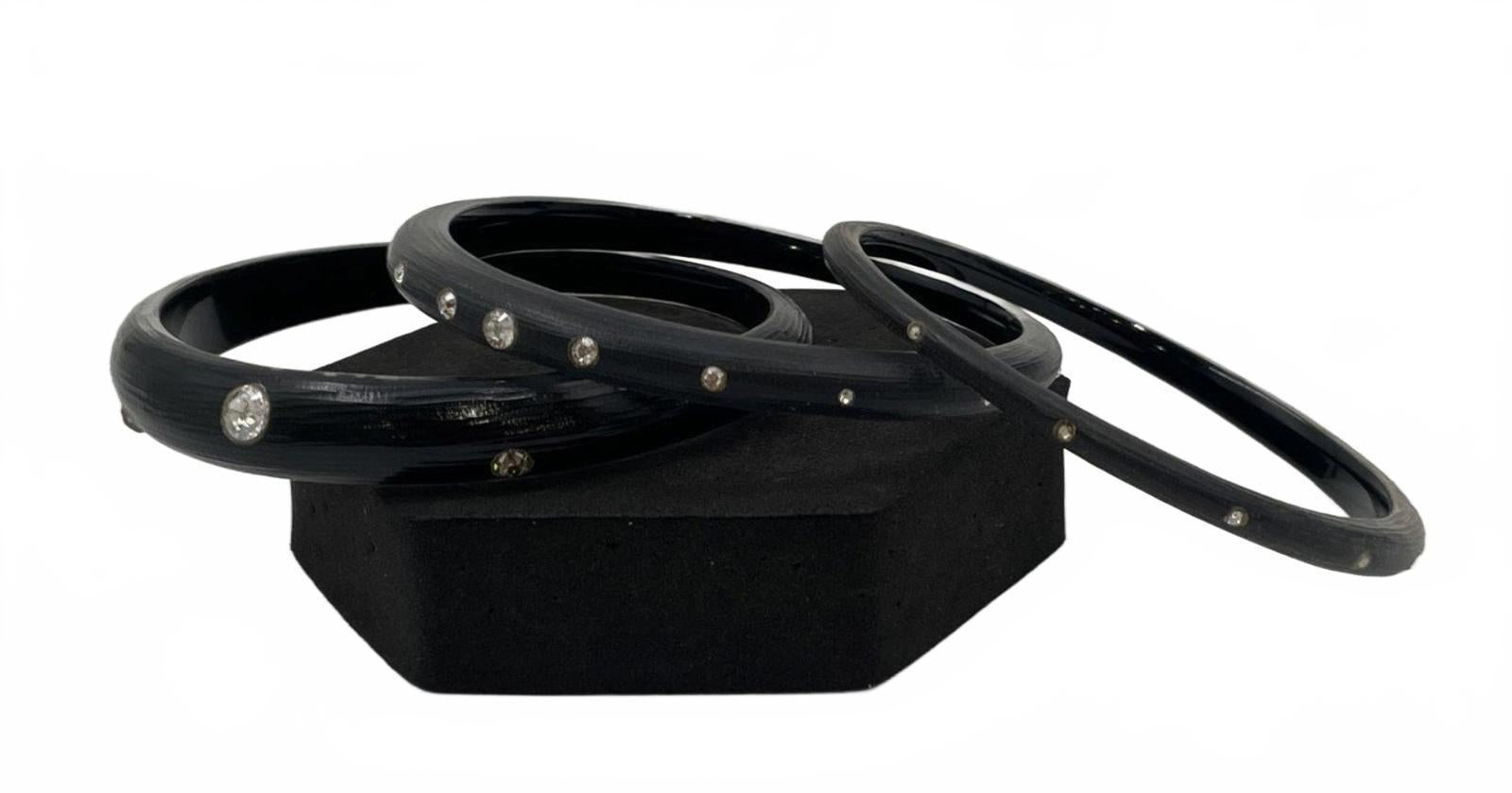 Three black lucite bangles with small crystal studs along the outer edge
