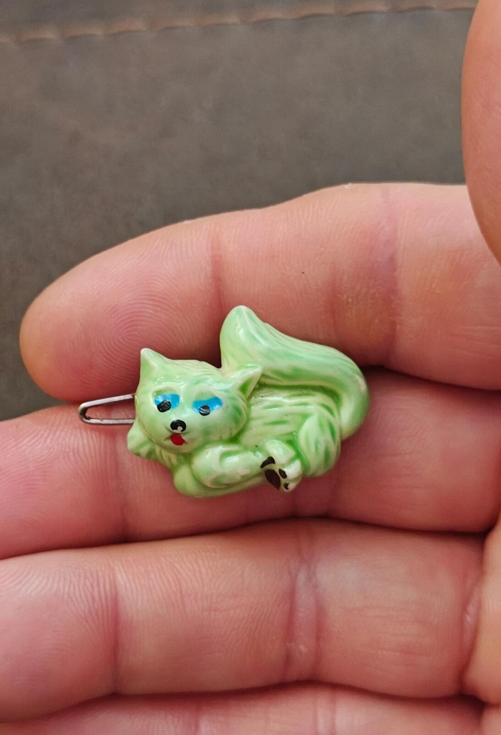 Small green cat hard plastic barrette with blue eyes, metal pin, held up close