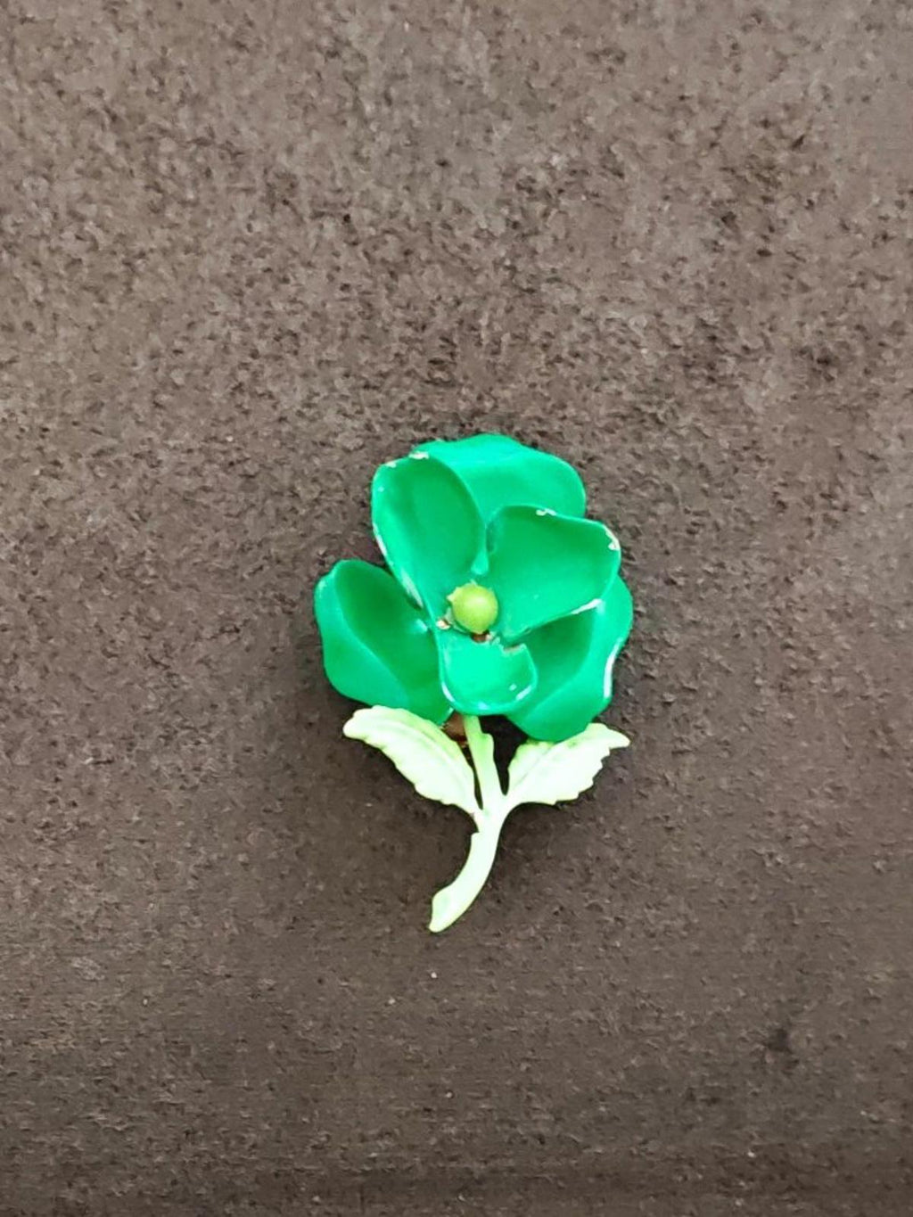 Green enamel flower statement brooch with gold center and pale green leaves.