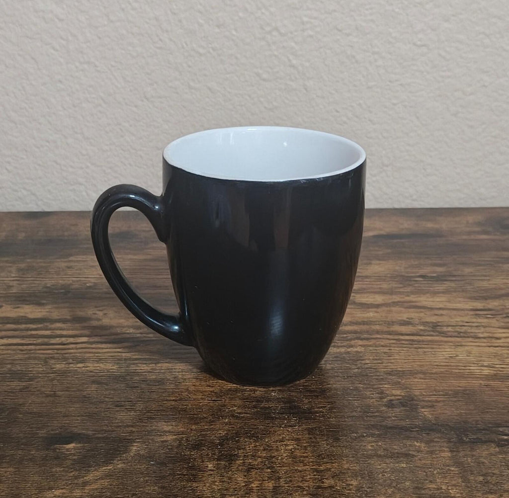 Black mug with handle and white interior rim, side view on tabletop
