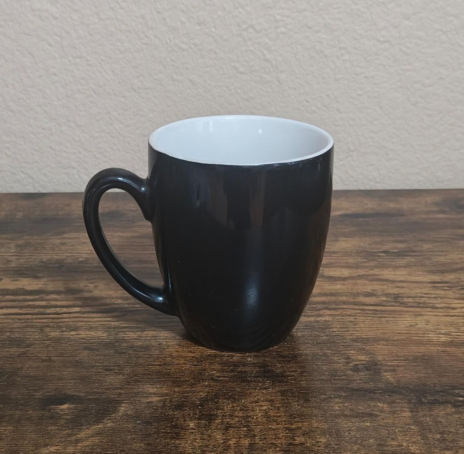 Black mug with handle and white interior rim, side view on tabletop