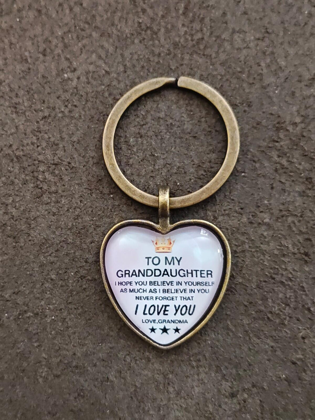 Brass-tone keychain with white heart pendant featuring “To My Granddaughter” and “I Love You”