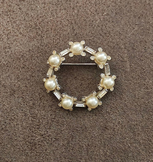 Silver-tone circular brooch pin with faux pearls and clear rhinestones, wreath frame on fabric
