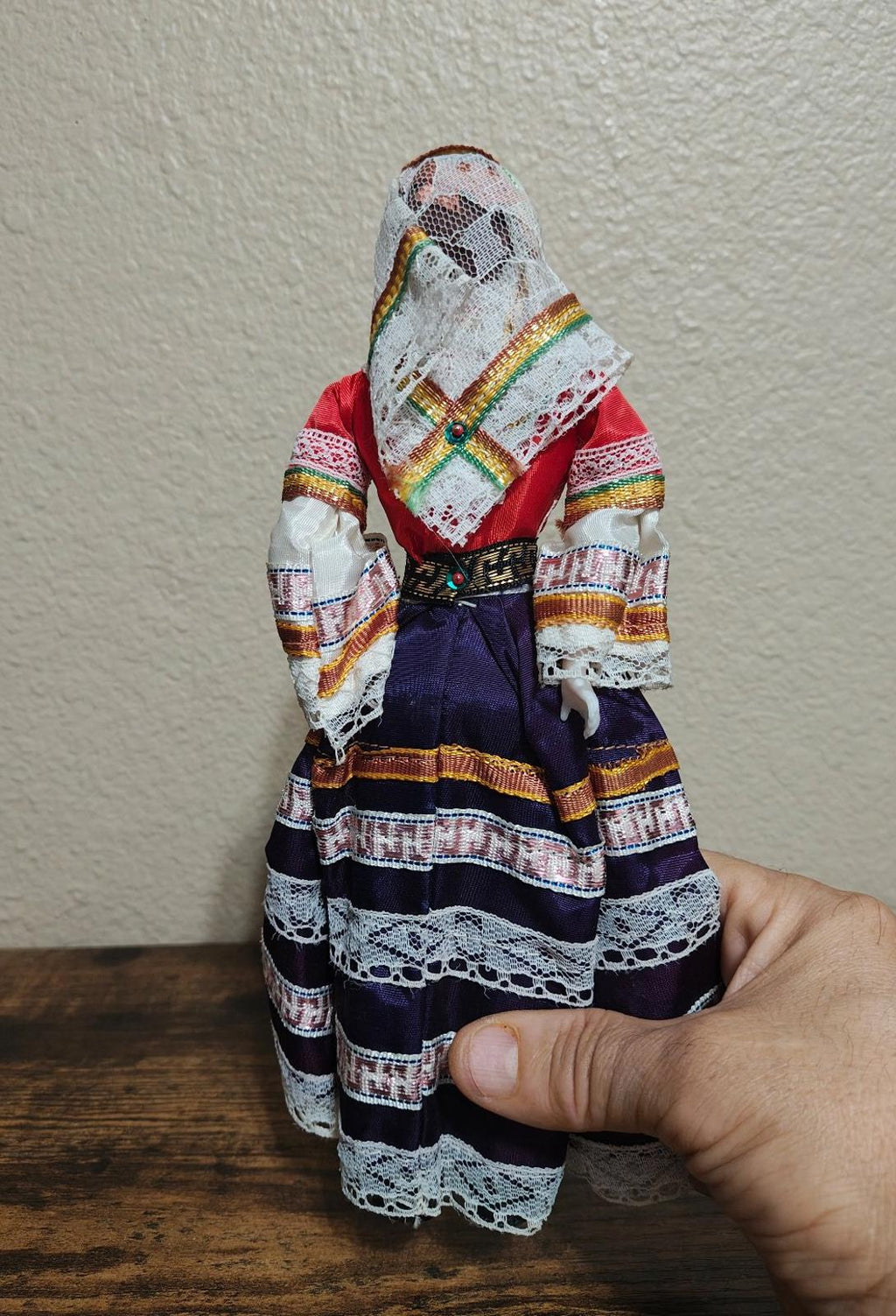 Female folk doll with white hooded headscarf and patterned long skirt in red and navy