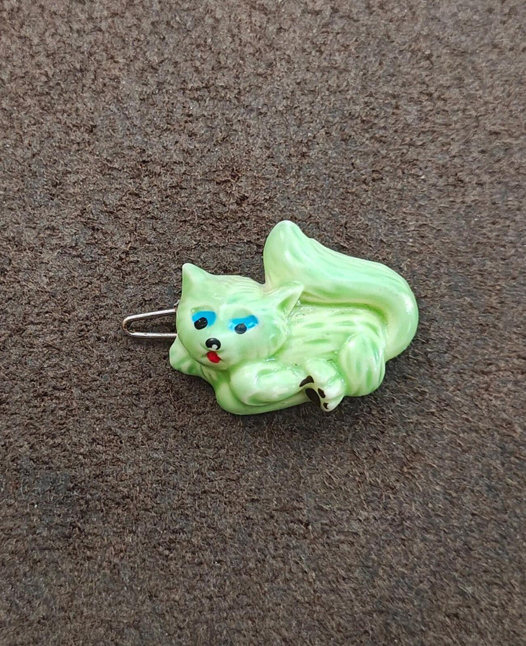 Green cat hard plastic hair barrette with painted face and metal pin on fabric