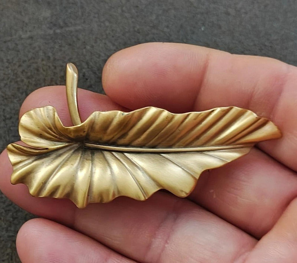 Gold-tone leaf brooch pin with textured veins and raised center, pointed clasp.