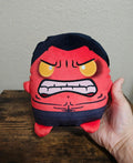 Red and navy angry-faced soft plush toy with long embroidered brows and mouth