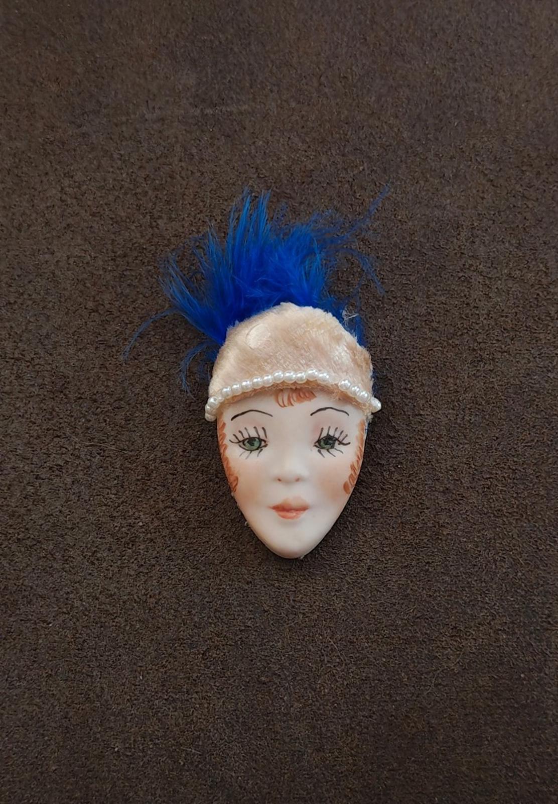Doll face pin brooch with blue feather and cream faux pearl headband