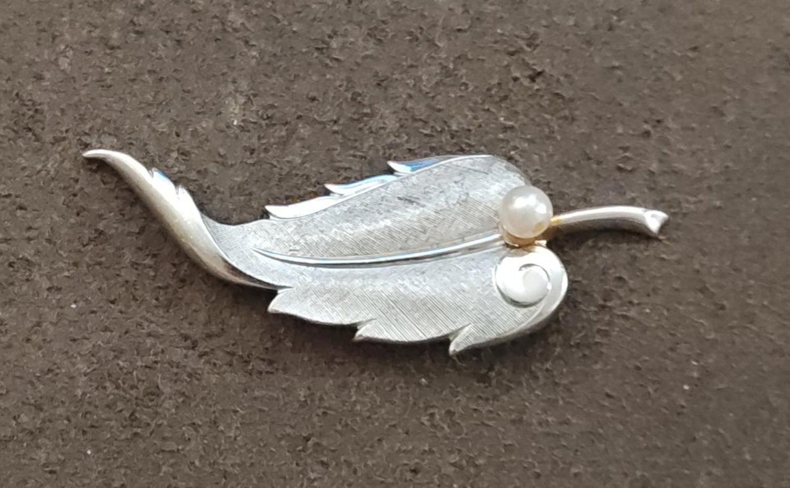 Silver leaf brooch on dark surface, textured design with cultured pearl at center