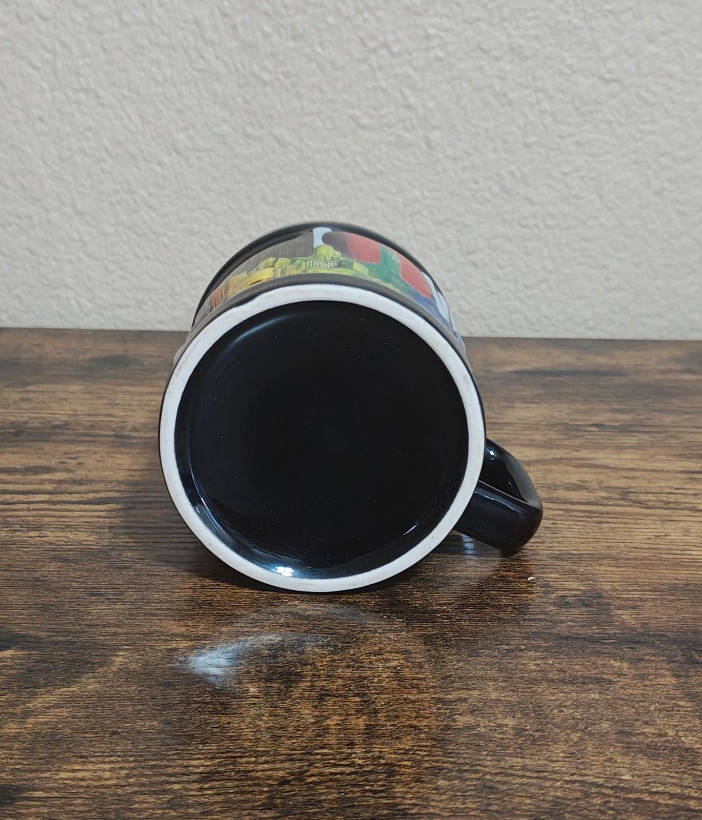 Black ceramic mug with colorful rim accents, open top facing up on tabletop