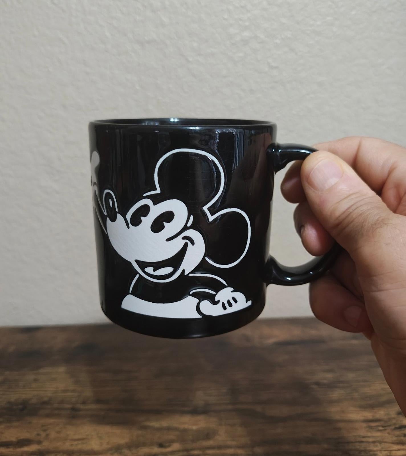 Black mug with white Mickey Mouse face graphic and side handle